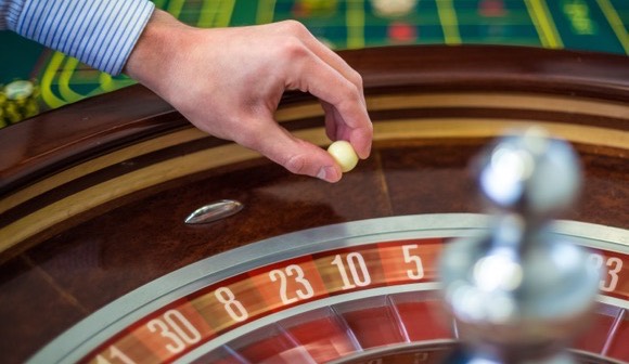 Mano del crupier lanzando la bola en la ruleta